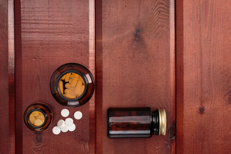 Heap of white pills and glass bottles for medicines on a wooden backgroundの写真素材