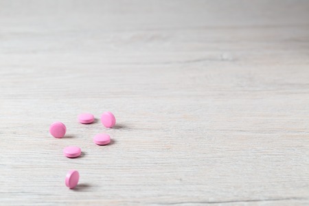 Heap of pink round pills on bright tableの写真素材