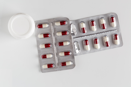 Pills blister packs and white pills bottle on white backgroundの写真素材