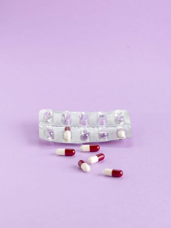 Blister packaging of red and white capsules on a colored backgroundの写真素材