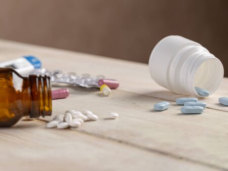 Glass and plastic bottles of medicine. Blue tablets and colored medical capsulesの写真素材