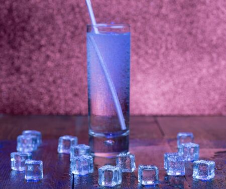 Glass of soda water and scattered melting ice cubes aroundの写真素材