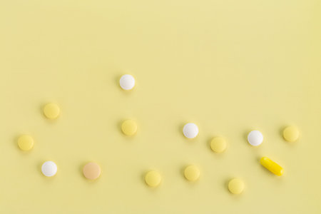 various round tablets and capsules with antibiotics on a yellow background