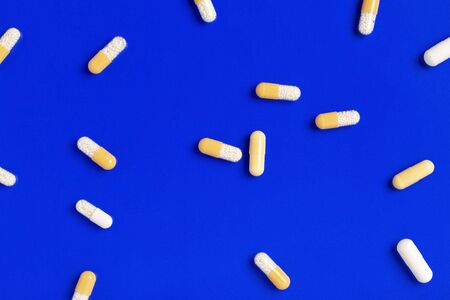 Yellow medicine capsules on a blue color backgroundの写真素材