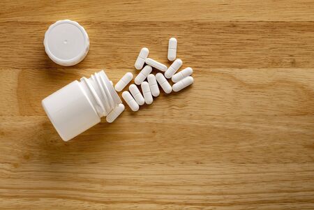 Medicinal bottle and white drugs on a wooden tableの写真素材