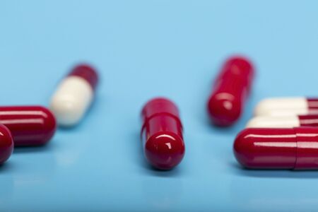 Red-white medicinal capsules on blue backgroundの写真素材