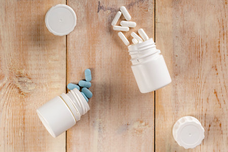 Home medicine.White plastic pill bottles and different pills. Wooden table