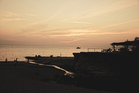 People on a rocky beach by the sea in the eveningの写真素材