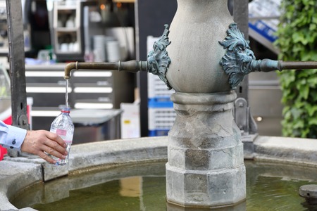 Man pours drinking water in a plastic bottle in a city parkの写真素材