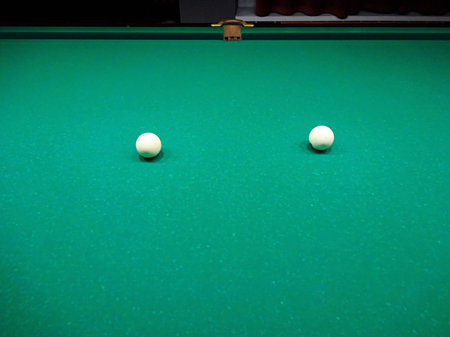 Ivory billiard ball on the green cloth of the table to play