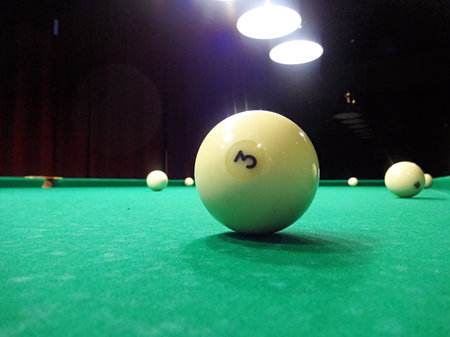 Ivory billiard ball on the green cloth of the table to play