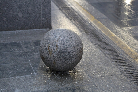 A large ball of gray stone on the pedestrian sidewalkの写真素材