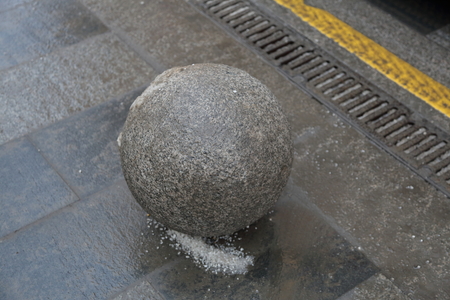 A large ball of gray stone on the pedestrian sidewalkの写真素材
