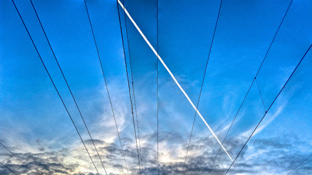 Symmetrical pattern of electrical wires on the blue sky backgroundの写真素材