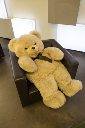 Big fluffy teddy bear sitting in a brown leather armchairの写真素材