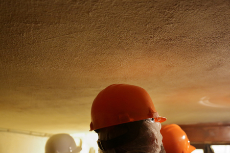 Man in an orange protective plastic helmet on his headの写真素材