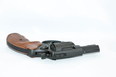 Small black handgun with a wooden handle on a white background