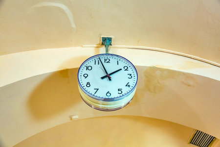 Round plastic watch with black arrows attached to the ceiling