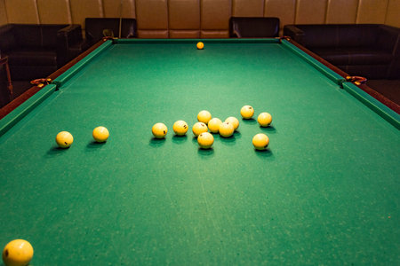 Large table with green cloth for playing billiards and ivory balls
