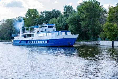 A small old ship sails along the river in a sunny dayの写真素材