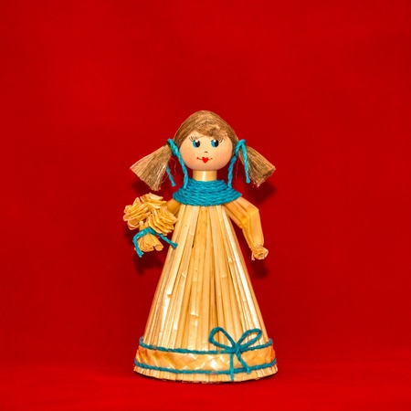 Toy doll girl handmade of straw on a red backgroundの写真素材