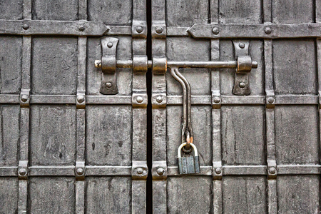 A large metal lock hangs on a fence made of wrought ironの写真素材