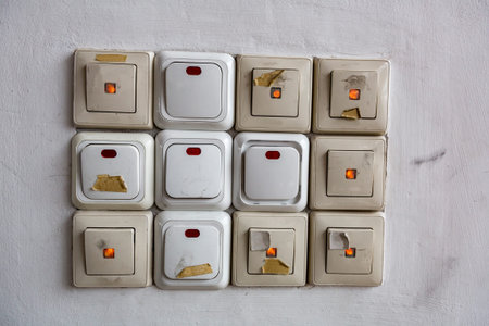 Twelve electric switches in a row on a light plastered wall