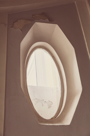 Small oval window in the wall of an old houseの写真素材
