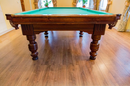 Large wooden table with green cloth for playing billiards