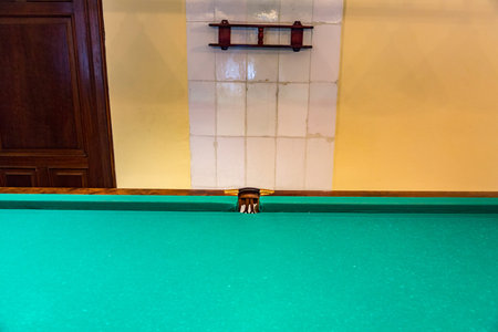 Large wooden table with green cloth for playing billiards