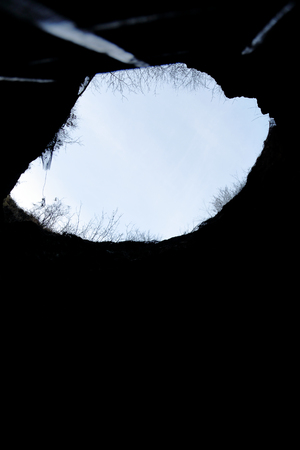 View of the sky and trees from the bottom of a stone mineの写真素材