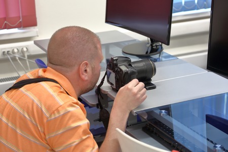 Red-haired bald man in an orange polo with a photo cameraの写真素材