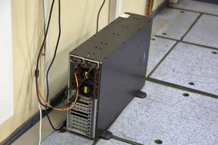 Black computer tower with wires on the floor of the room
