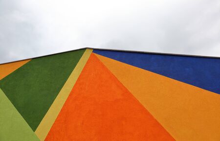 Colorful wall with abstract geometric pattern on a cloudy sky backgroundの写真素材
