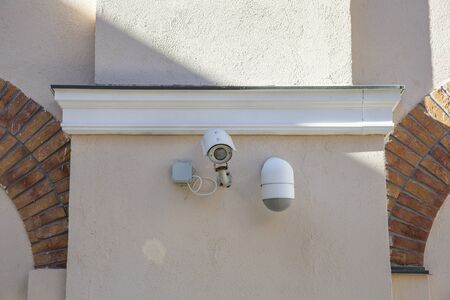 Outdoor white security camera on a stone wall with brick fragmentsの写真素材