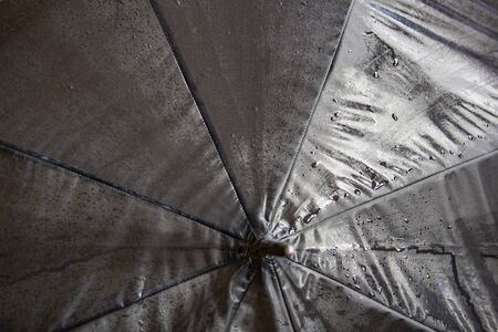 Wet textured surface of a black umbrella with drops of water after rainの写真素材
