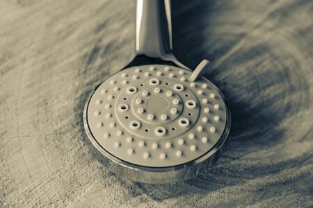 Round shower head made of metallic color plastic on a natural wood backgroundの写真素材