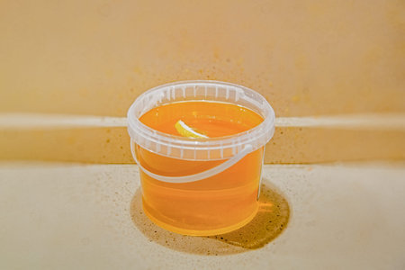 Plastic jar with honey and a slice of lemon with zest