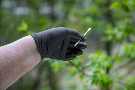 Doctor's hand in a rubber glove for medical manipulations. Green leaf background