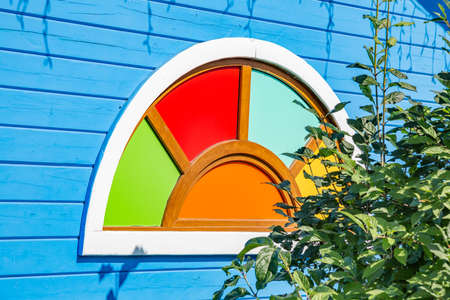 The idea of decorating a multicolored window opening in a wooden wall of a village houseの写真素材