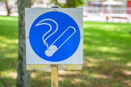 Smoking area in a public park. Old weathered sign in white and blue colorsの写真素材