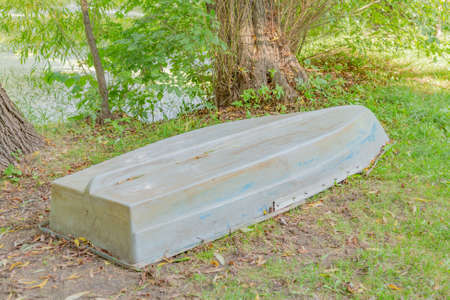 Old abandoned iron boat near a duckweed pond in the daytimeの写真素材