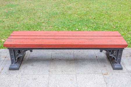 A recreation bench made of boards and wrought iron in a city park in summer