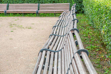 A recreation bench made of boards and wrought iron in a city park in summerの写真素材