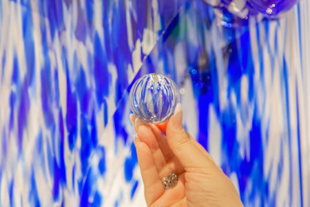Woman's hand holding a transparent glass ball with reflection abstract pattern