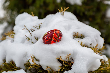 Painted festive Easter egg in white winter snow