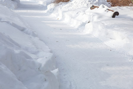Snow-covered deserted hiking trail in a city park in cold winter