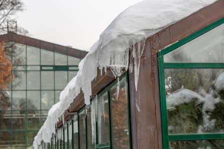 Winter icicles hanging from the eaves of the glass buildingの写真素材