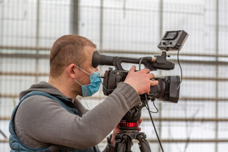 An adult caucasian man in a protective face mask takes a video of the camera