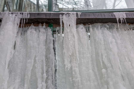 Winter icicles hanging from the eaves of the glass buildingの写真素材